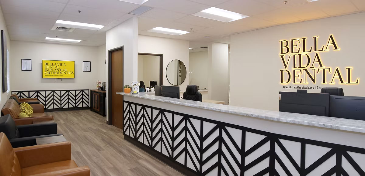 The image shows an interior view of a dental office reception area with a modern design featuring a sign that reads Bella Vida Dental.