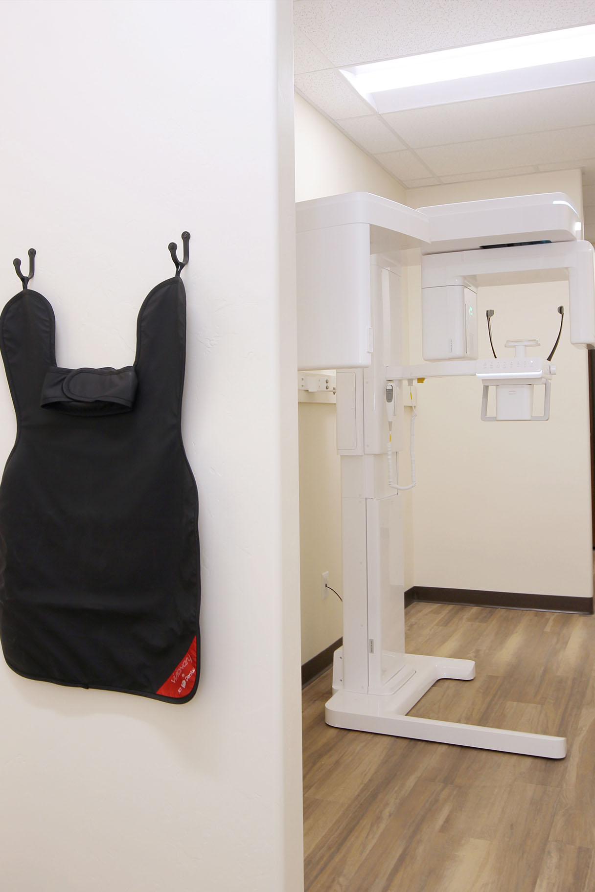 An apron hanging on a wall next to a medical equipment device in an office setting.