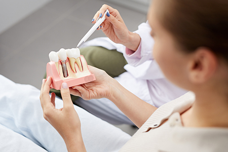 Woman holding a pink toothbrush with toothpaste in front of her mouth.