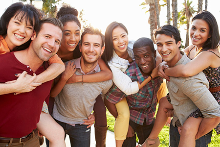The image depicts a group of people posing together outdoors during daylight, with a cheerful atmosphere.